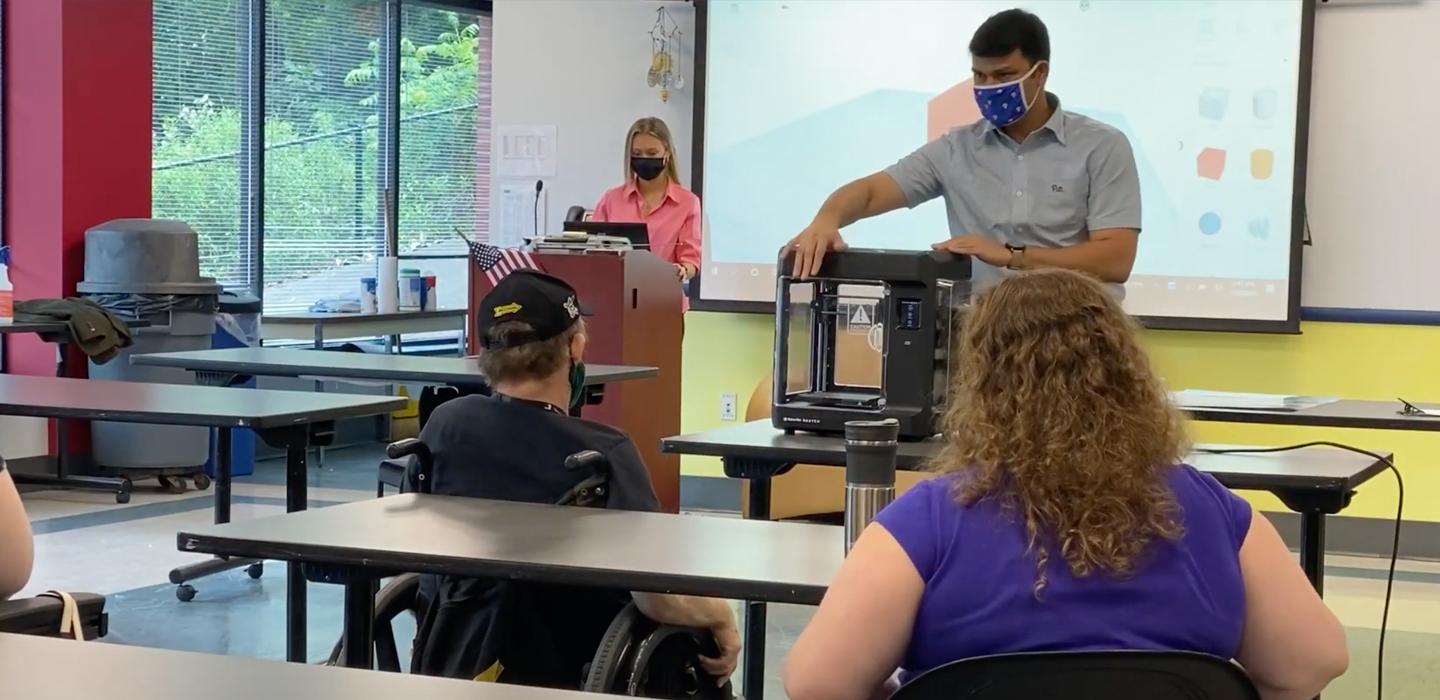 Man presenting a machine in front of a class