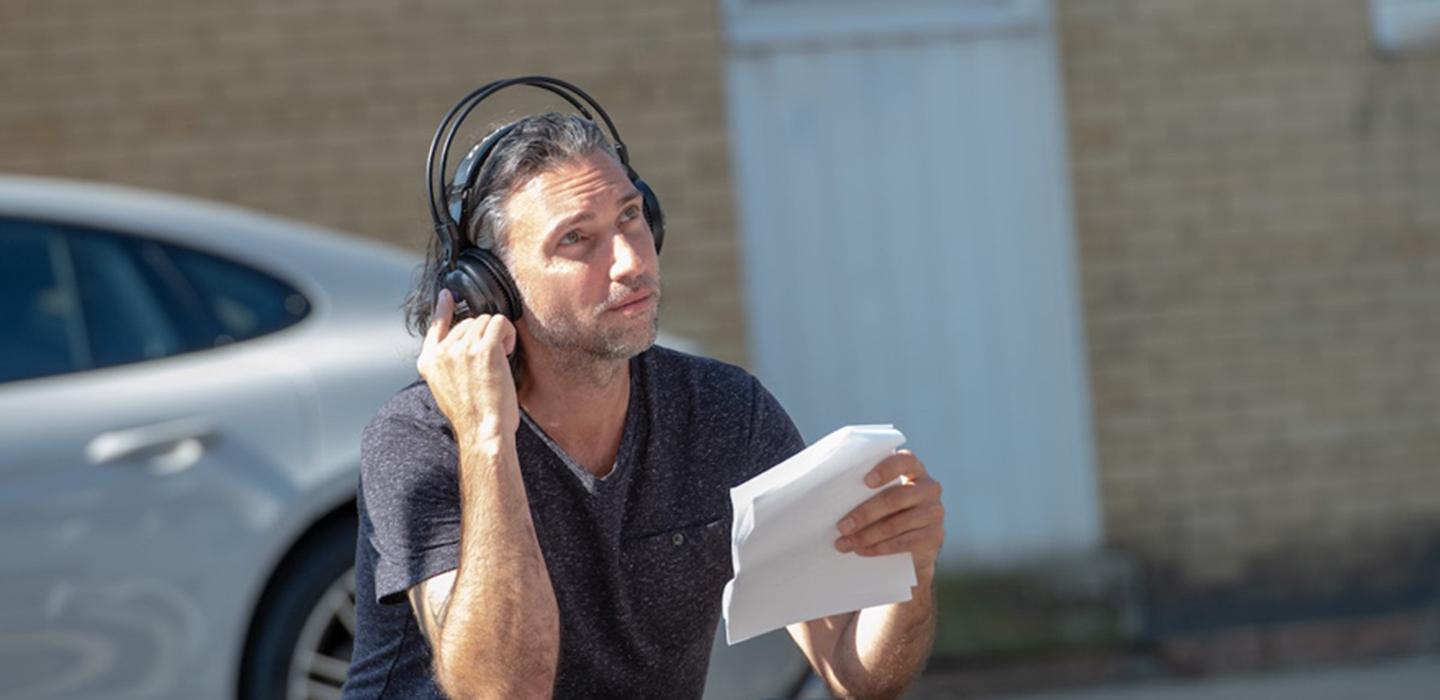 Paolo Pilladi in a dark shirt and headset, holding papers