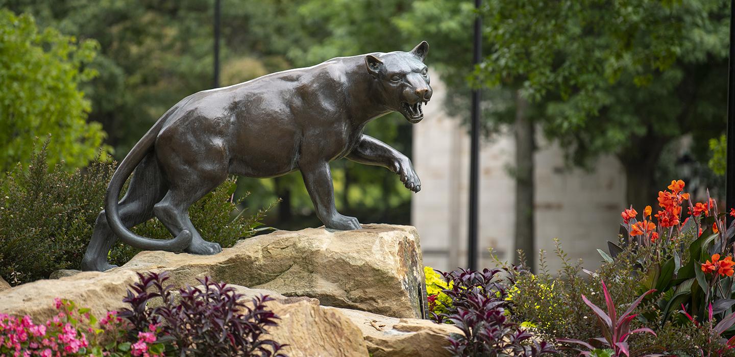 Panther statue next to colorful flowers