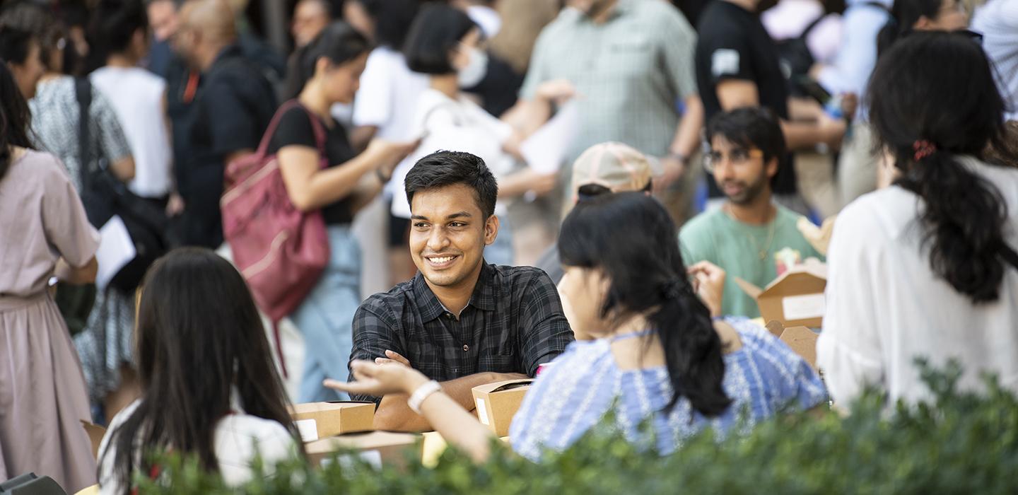 Students sitting at a picnic, smiling 