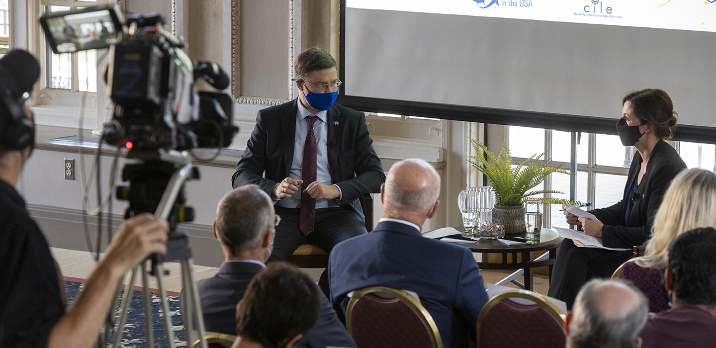 Valdis Dombrovskis speaking with Erica Owen in front of crowd and camera crew