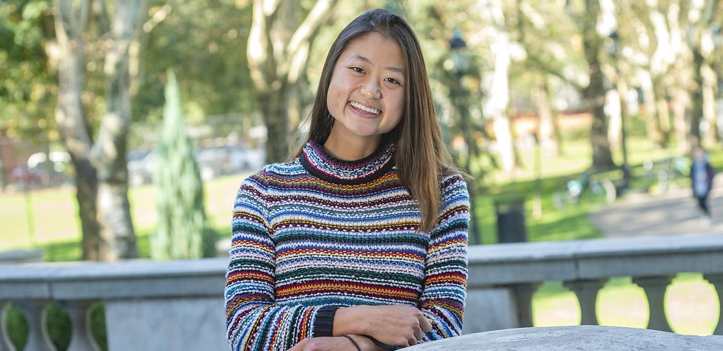Yunge Xiao sitting outside in a striped sweater 