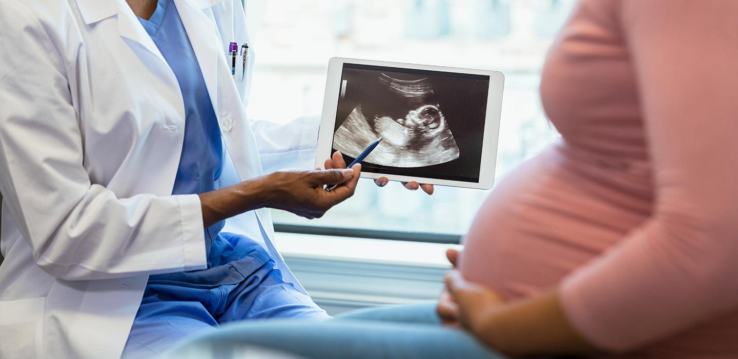 Health professional showing ultrasound to pregnant woman 