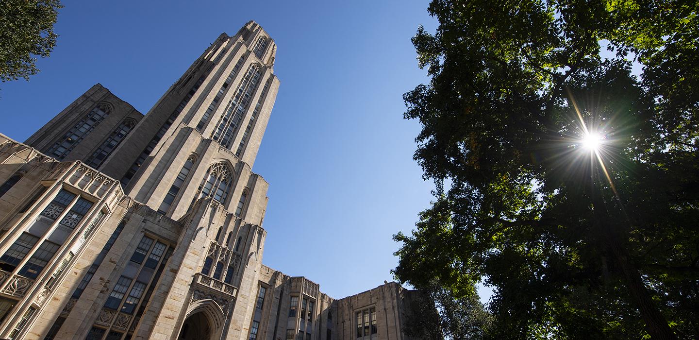 Cathedral of Learning next to trees on a sunny day 