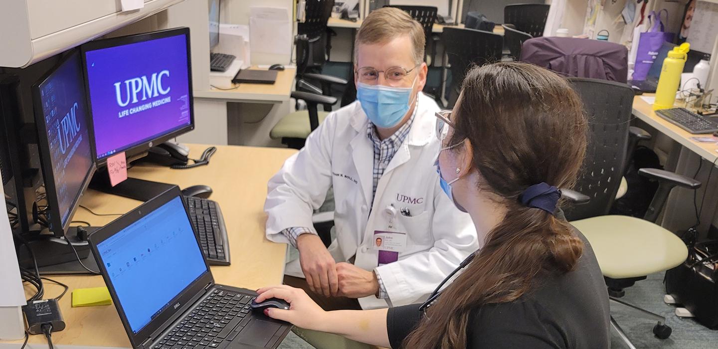 UPMC doctor speaking to student at a desk 