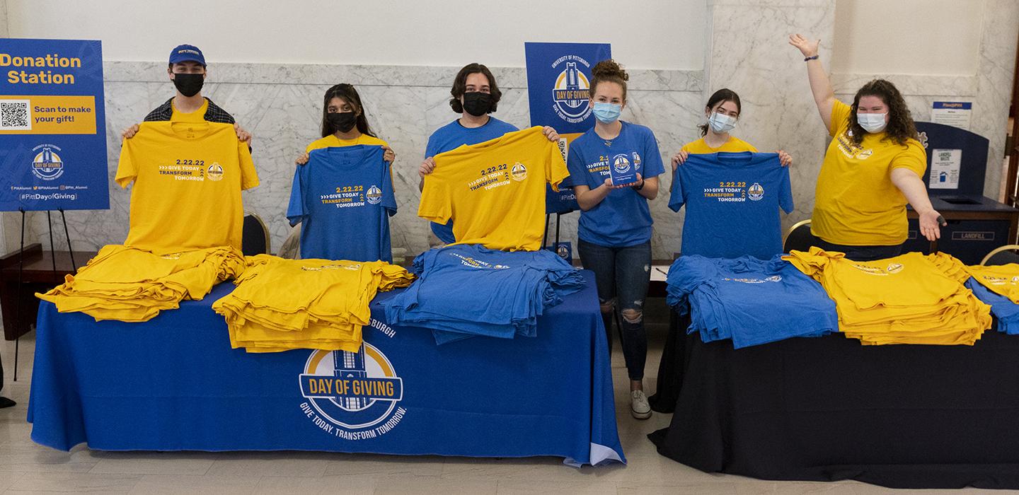 People holding blue and yellow Pitt Day of Giving shirts