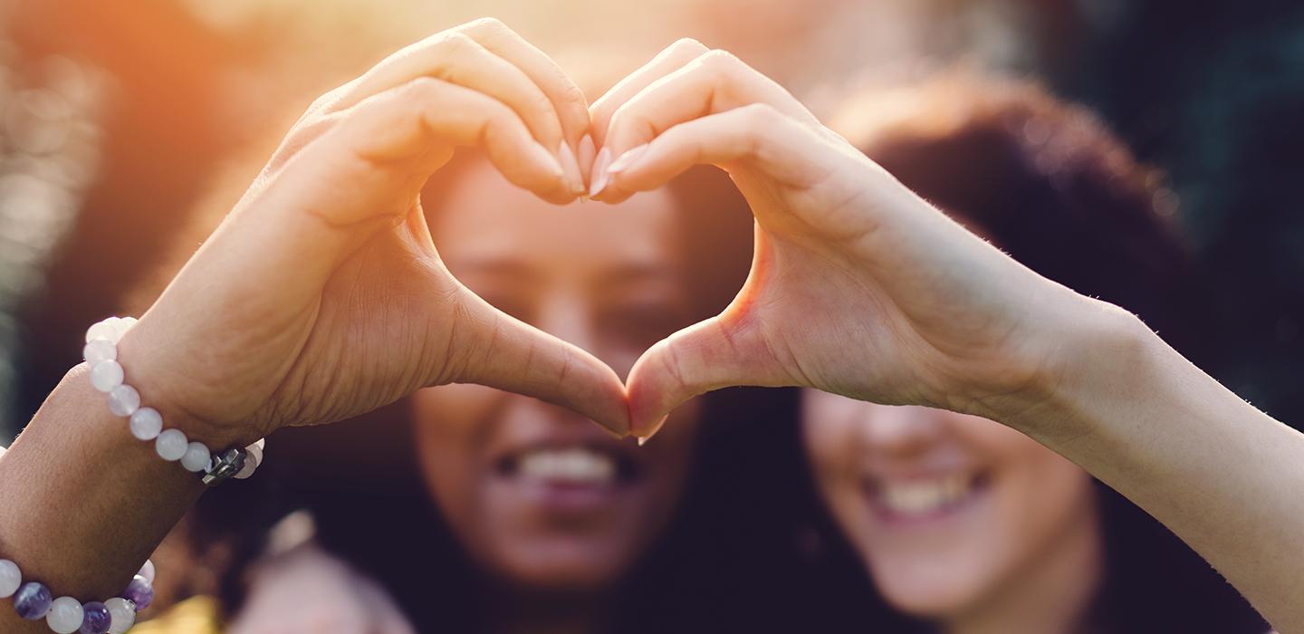 Two people forming a heart shape with their hands