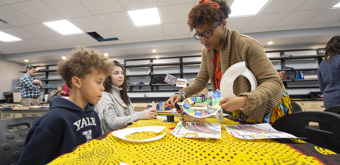 Woman teaching children at a table with colorful crafts