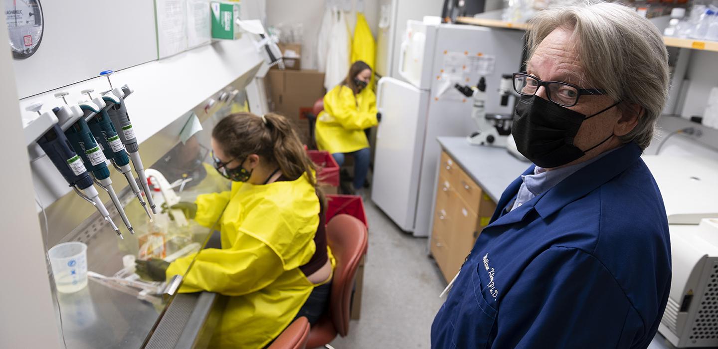 William Klimstra and workers in yellow gowns in a lab
