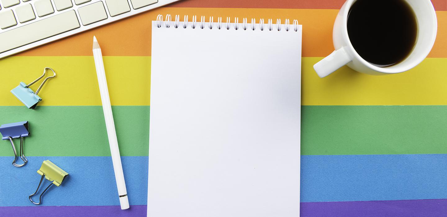 Notebook, pencil, coffee cup and keyboard on a rainbow background