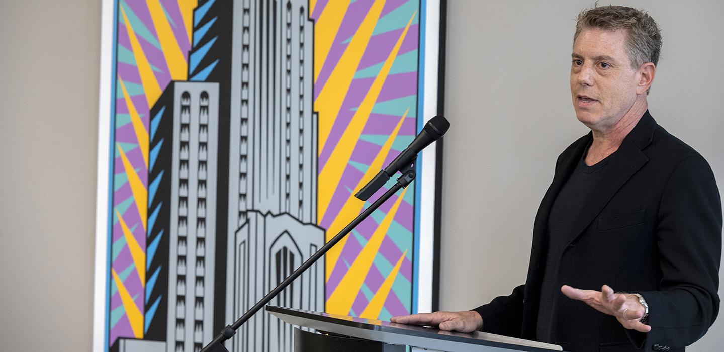Burton Morris speaking at podium next to Cathedral artwork
