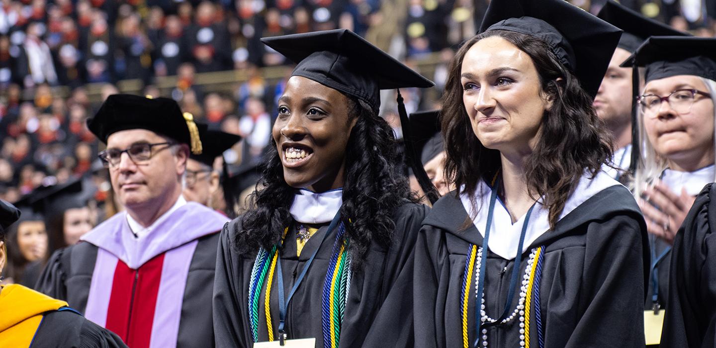 Graduating students smiling in the crowd 