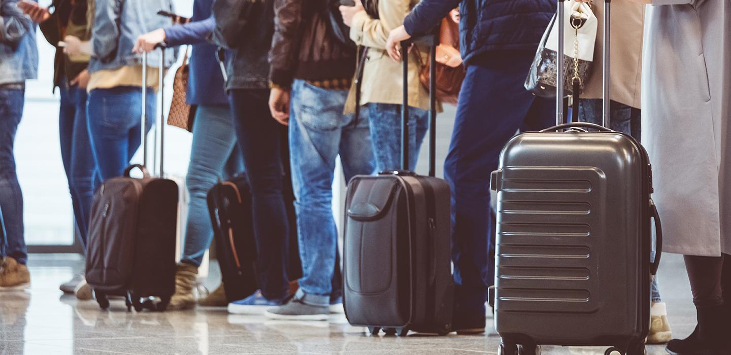 a line of people with rolling suitcases