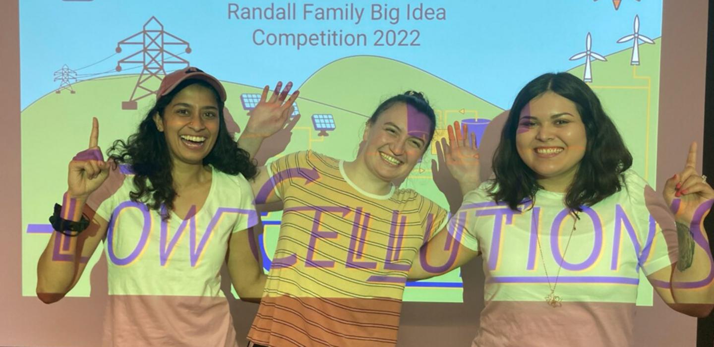 Winning team posing and smiling in front of projector 
