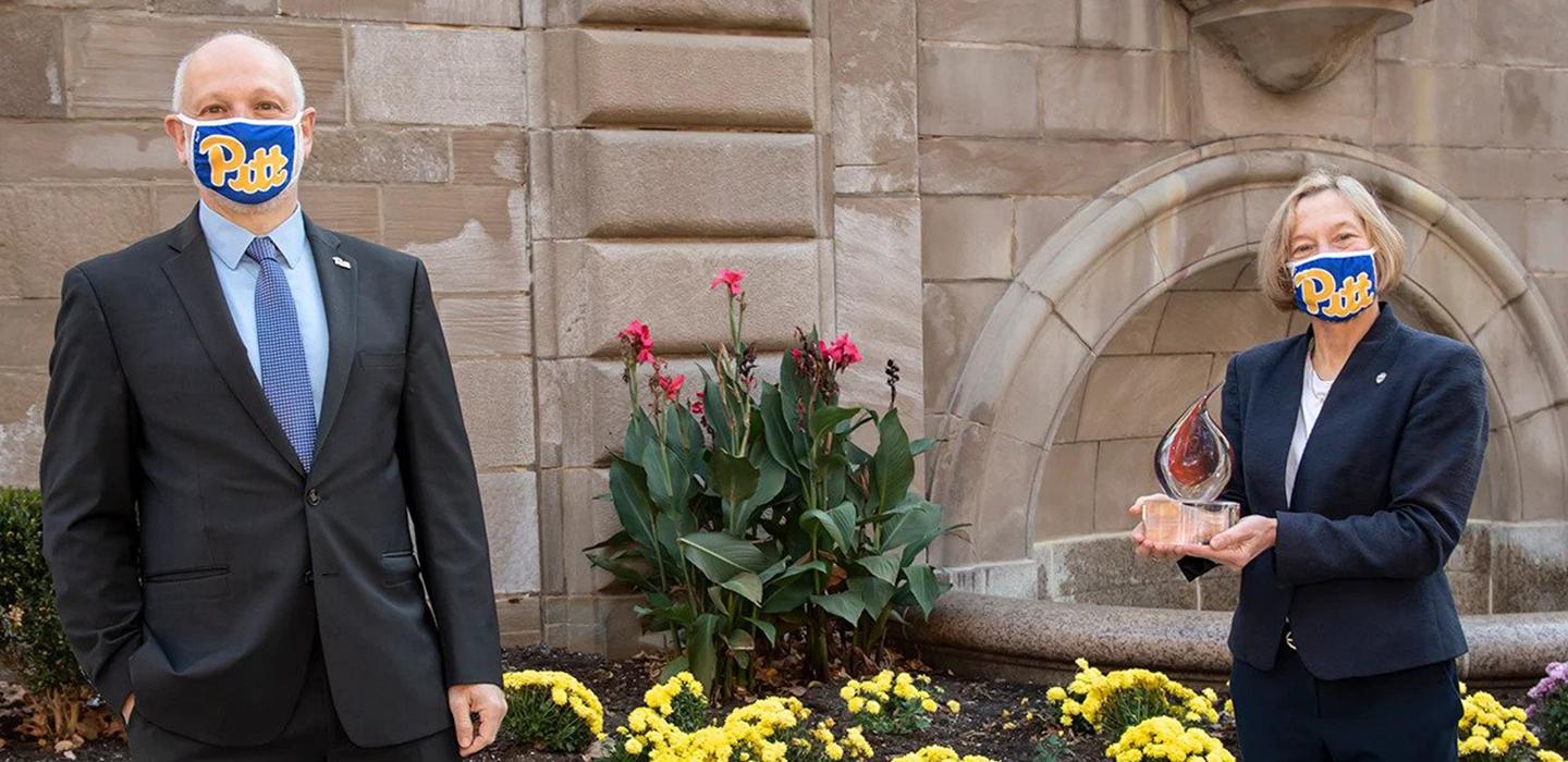 Two people, a man and a woman, in Pitt face masks and suits