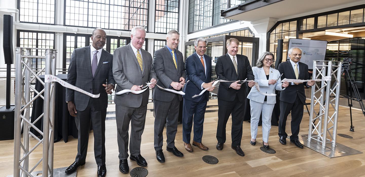 Seven people in suits cutting ribbon during opening