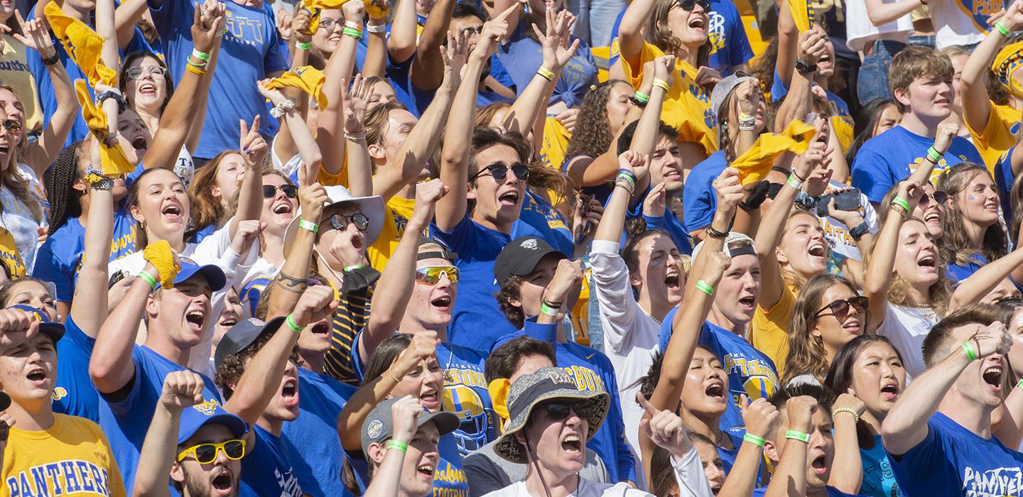 Pitt fans wearing blue and yellow cheering during homecoming
