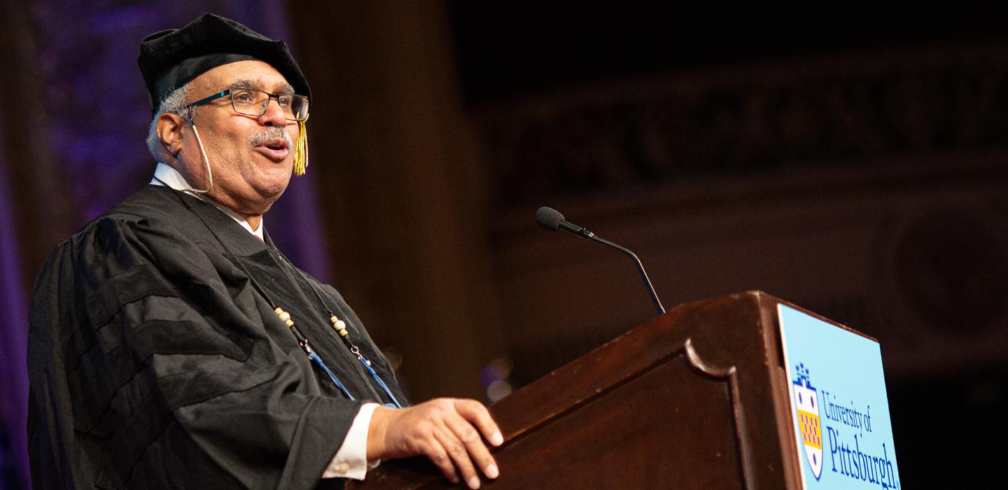 Georges Benjamin in cap and gown speaking at the commencement ceremony