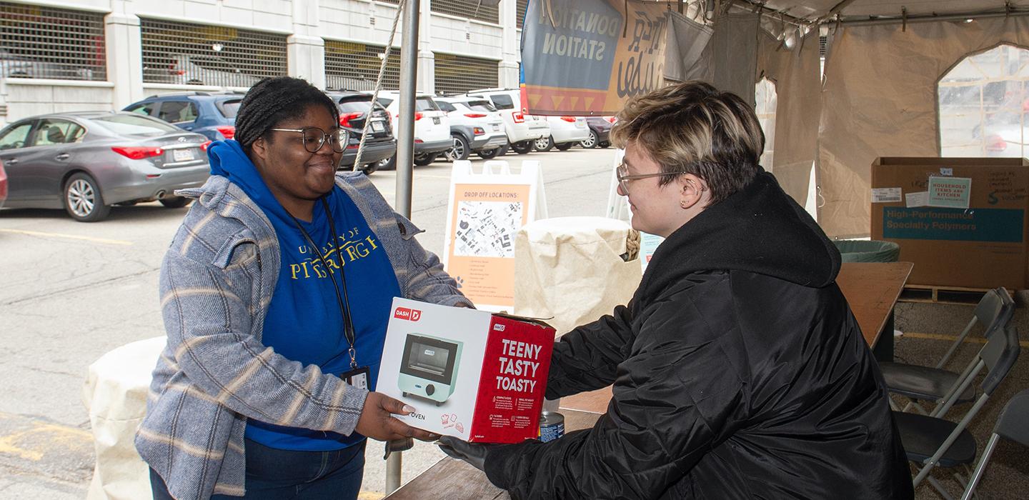 Woman donating toaster during Clutter for a Cause at a table outside