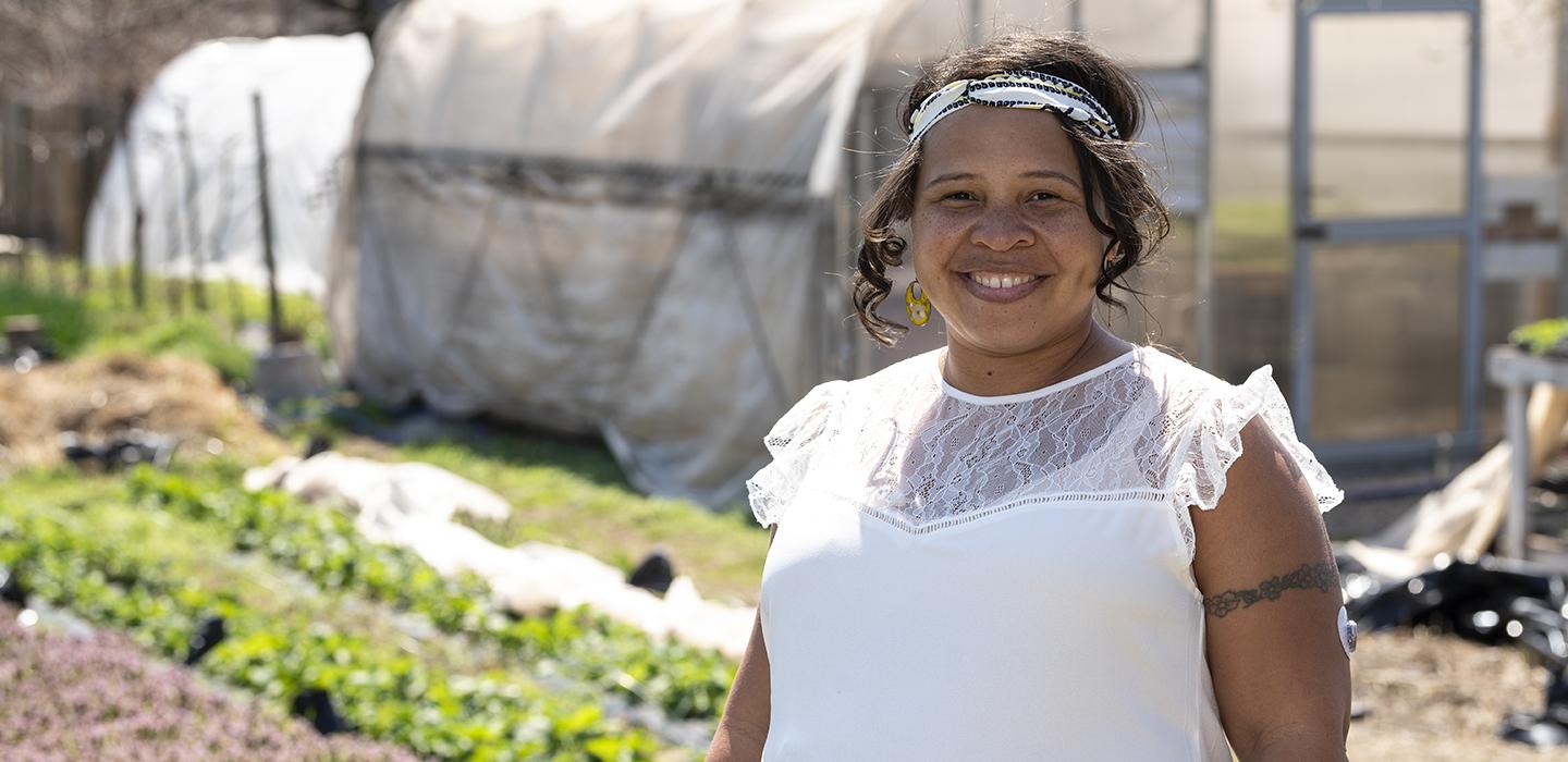 a person in front of a greenhouse and garden