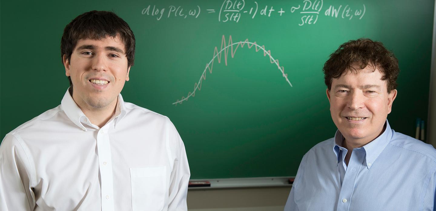 the Caginalps at a chalkboard with figures drawn on it