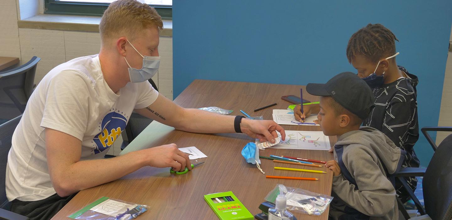 a Pitt person helping two kids color