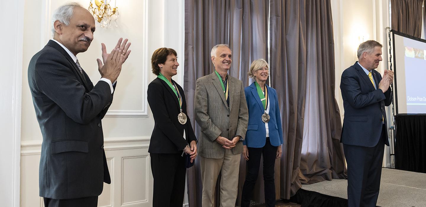 the three winners posing with people clapping near them