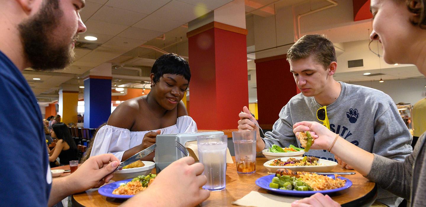four students gathered around a table eating