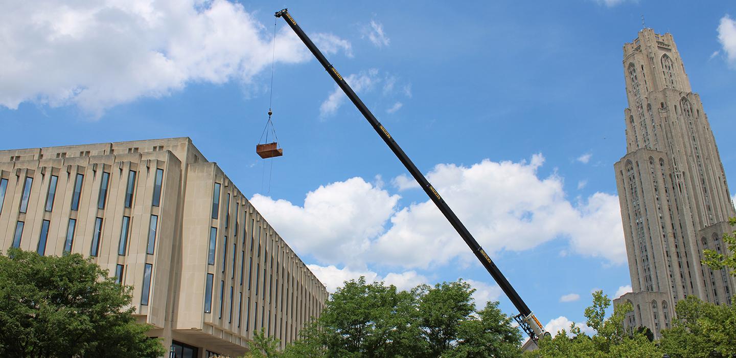 a crane hoisting something over Hillman Library