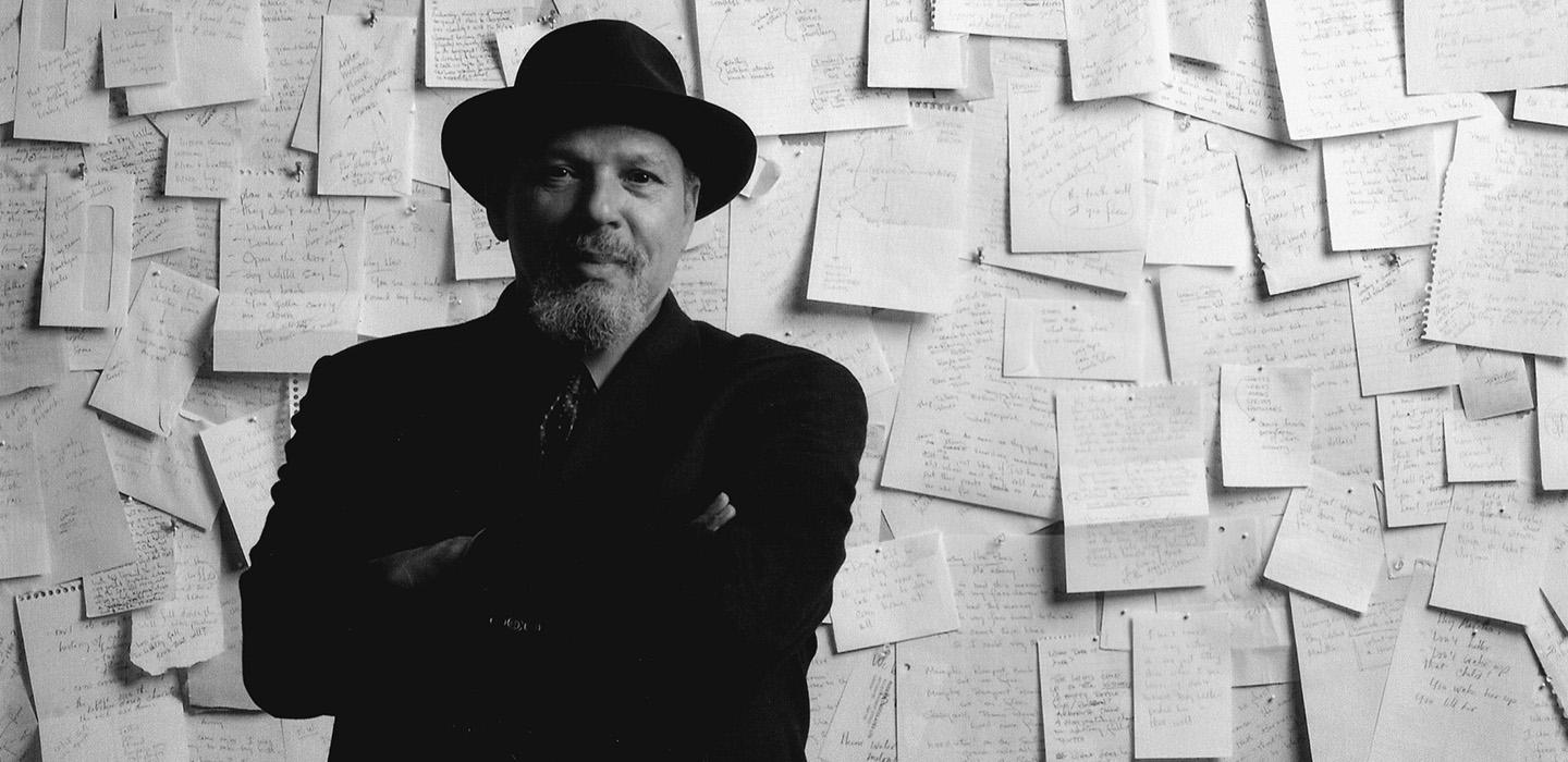 Wilson standing in front of a wall papered with notebook pages