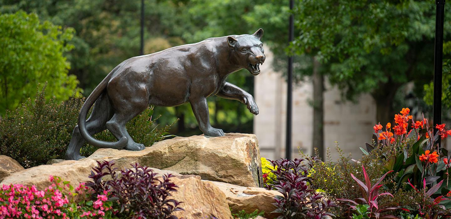 a Panther statue surrounded by lush flowers