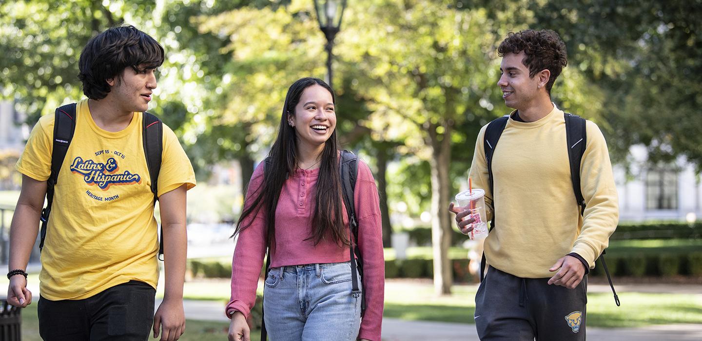 three students smiling, one wearing an LHHM shirt