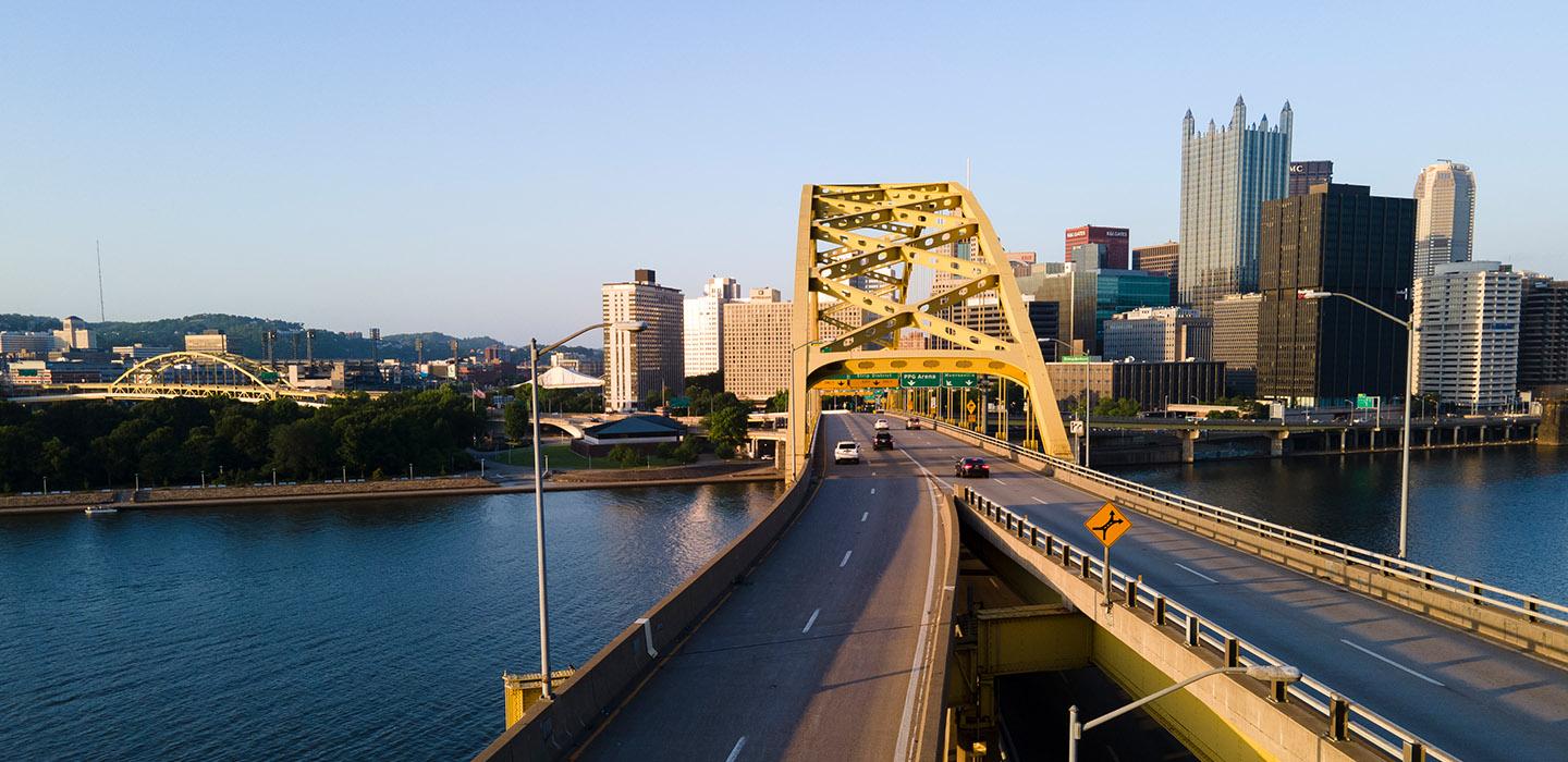 the long road and arch of a yellow bridge in Pittsburgh