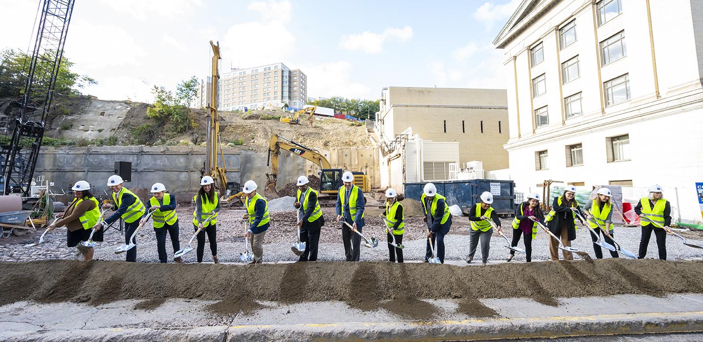 multiple people symbolically digging a shovel of dirt