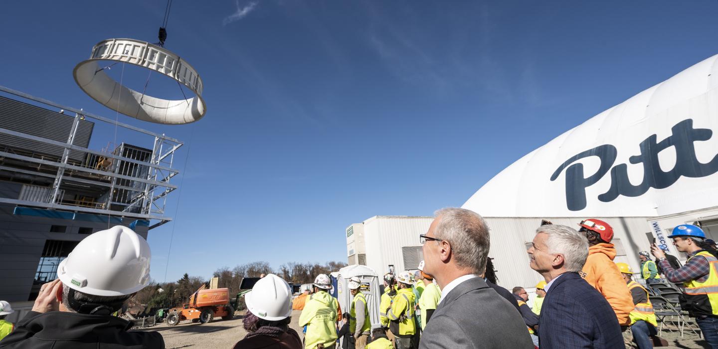 a large cylinder being placed atop a building with a crowd watching