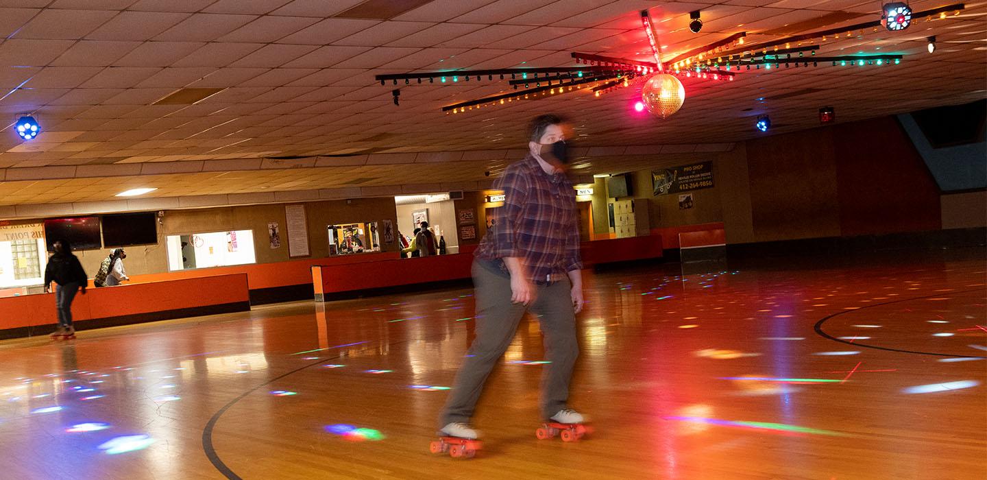 a person at a skating rink with festive lights shining down
