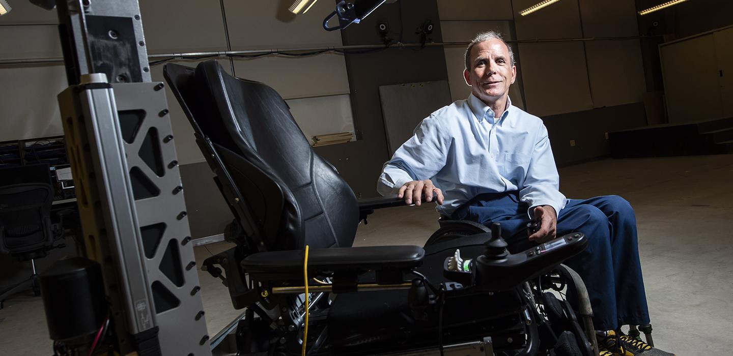 Cooper sits next to an electric wheelchair