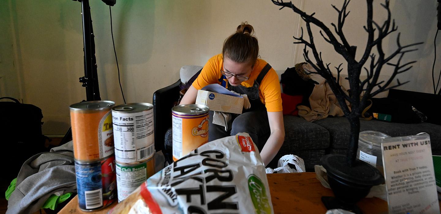 A volunteer in a yellow T-shirt sorts boxes of food donations