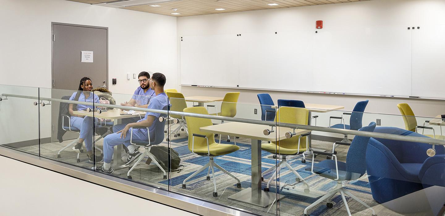 Students in scrubs sit in a lofted study area in Salk Hall