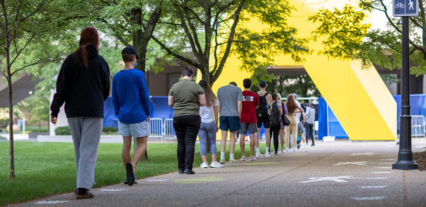 A line of people stand outside 