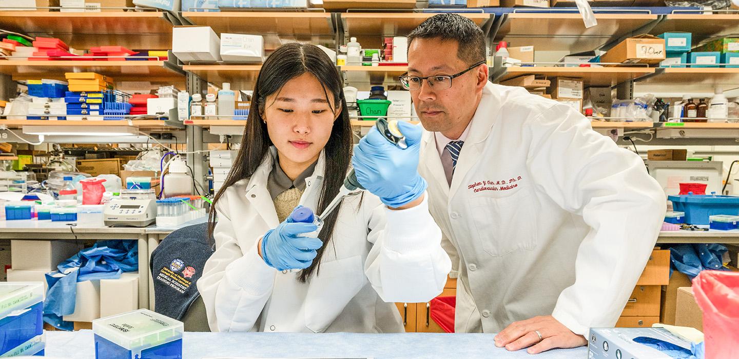 Two people in white coats work in a lab