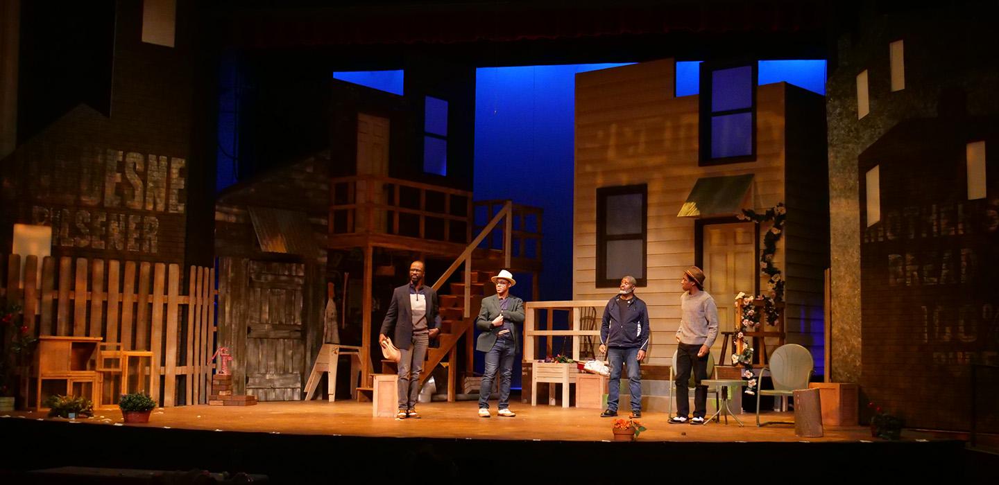 Four people stand on a stage