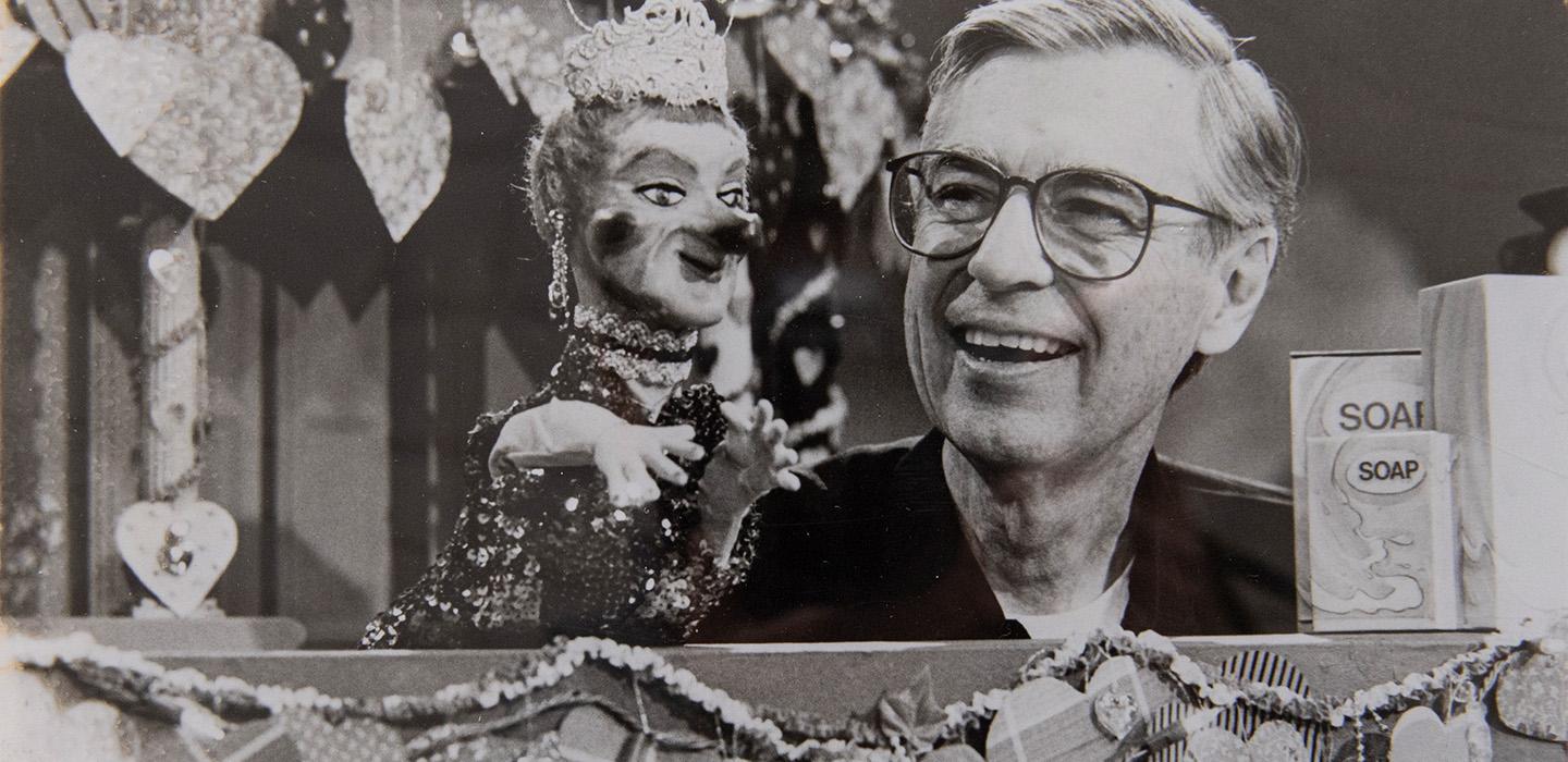 Fred Rogers controls a puppet in a black-and-white archival photo