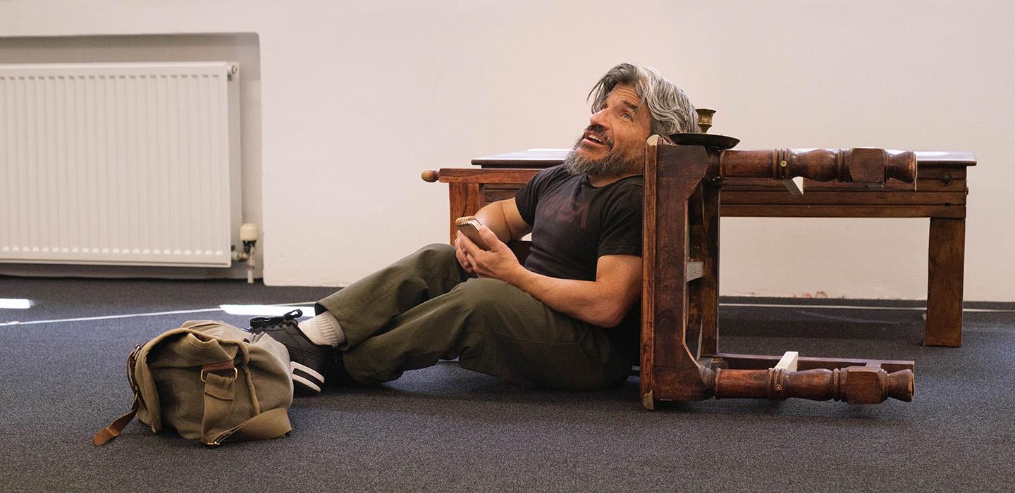 A person with Dwarfism delivers a monologue while leaning on an overturned table