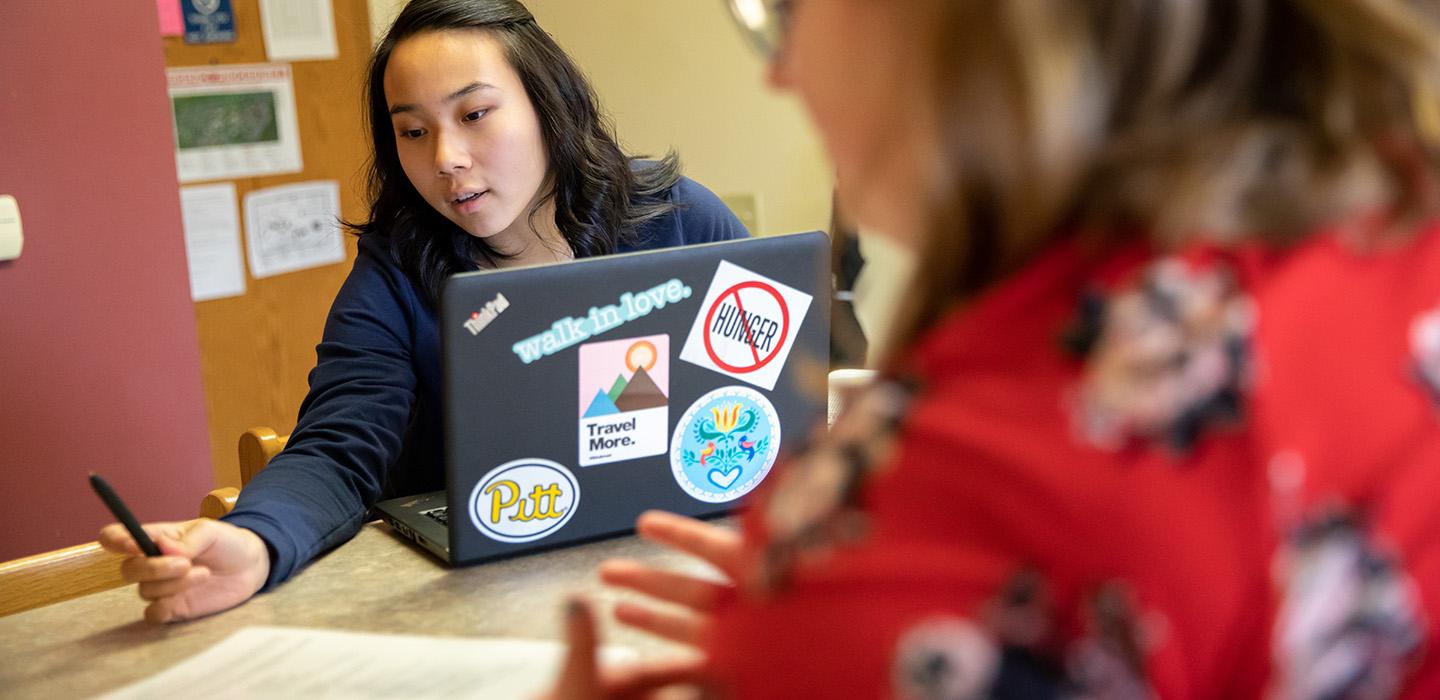 Two people discuss an assignment while studying in a dorm on the Bradford campus