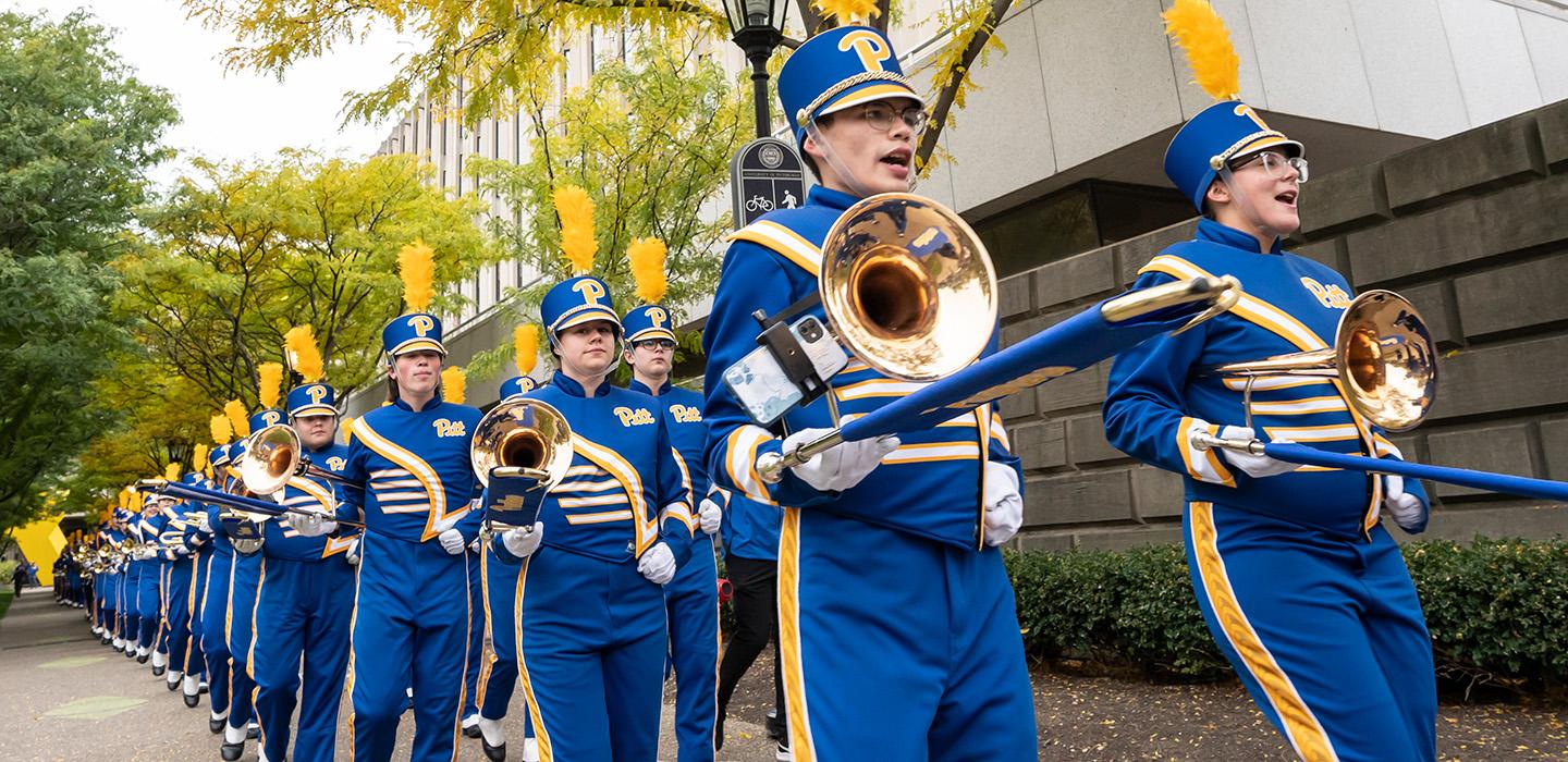 A band in blue and gold uniforms marches in two single file lines
