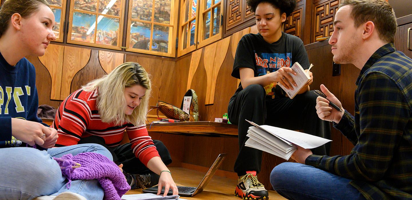 Students study front papers and laptops on the floor