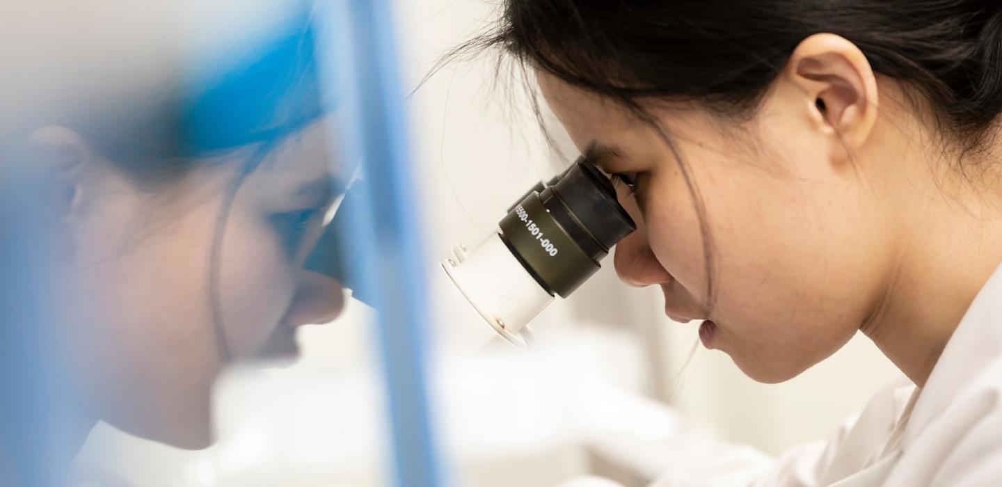 a profile of a scientist looking through a microscope