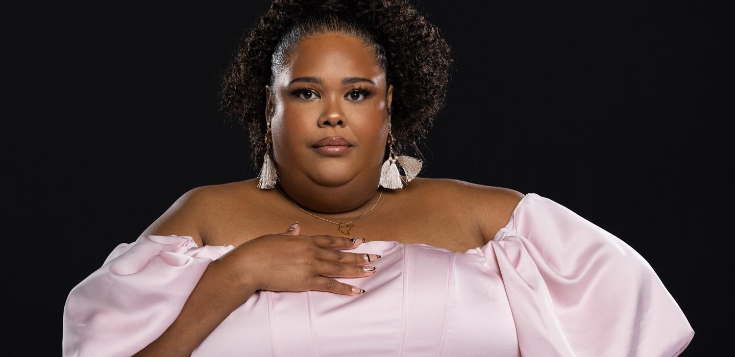Zuly in a pink dress in front of a black background
