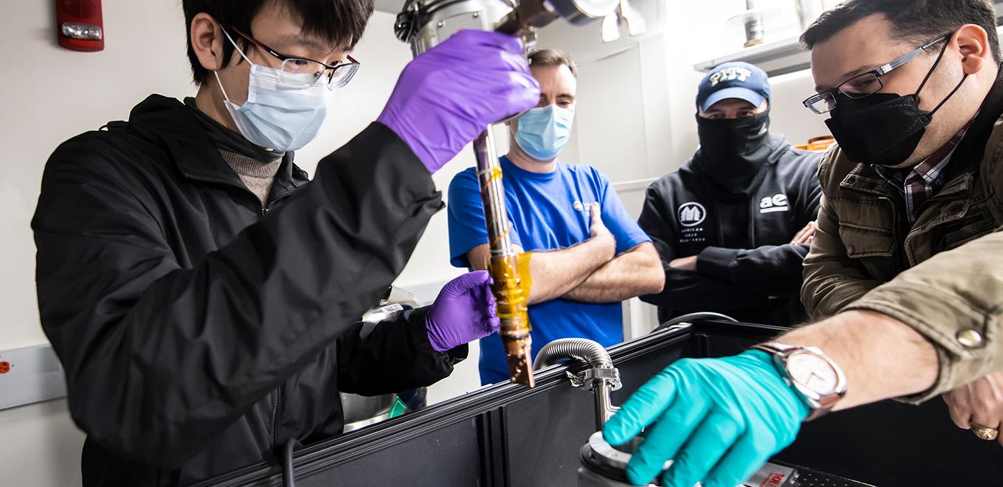 People gather around a machine that makes quantum computing parts